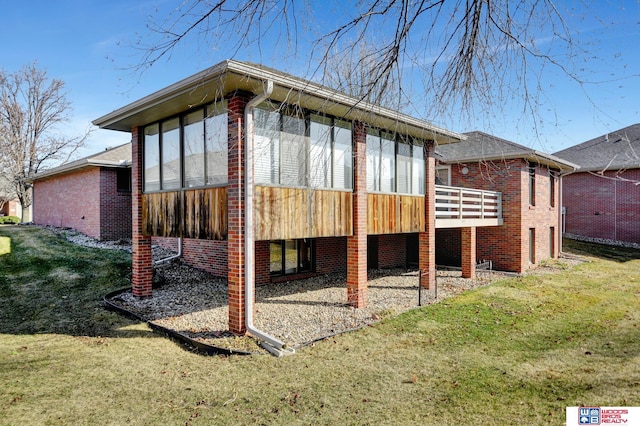 back of property with a lawn, brick siding, and a sunroom