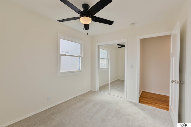 unfurnished bedroom with a closet, light colored carpet, baseboards, and ceiling fan