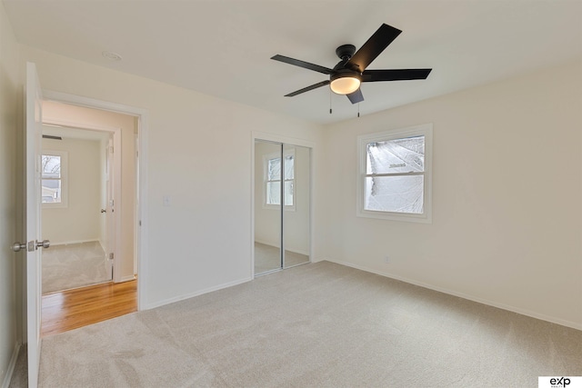 unfurnished bedroom featuring ceiling fan, light colored carpet, a closet, and baseboards