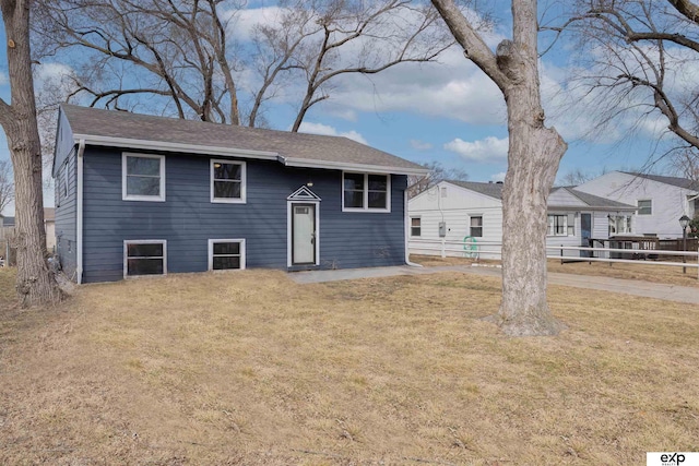 raised ranch with a front lawn and fence