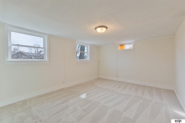 basement featuring light carpet, plenty of natural light, and baseboards