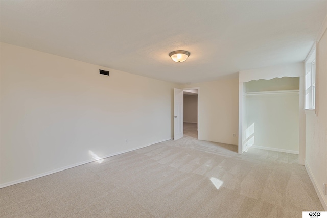 spare room with baseboards and light carpet