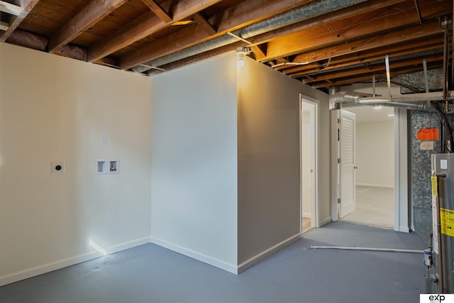 basement featuring baseboards and water heater