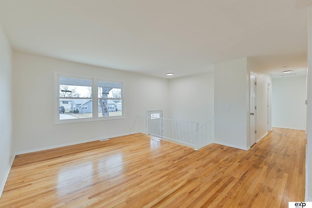 unfurnished room with visible vents, wood finished floors, and baseboards