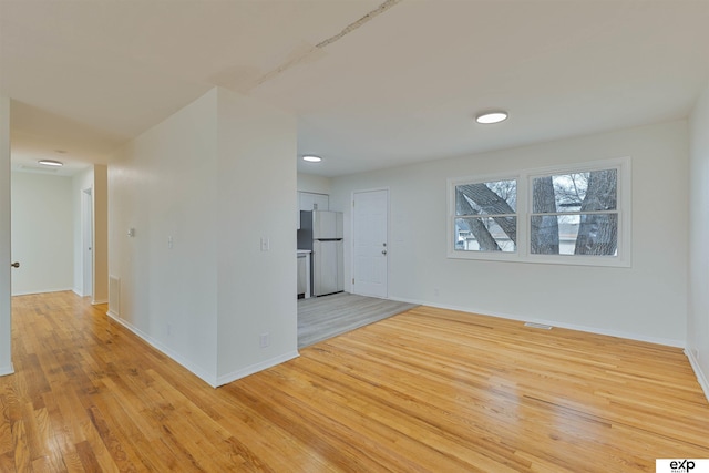 empty room featuring visible vents, baseboards, and light wood-style flooring