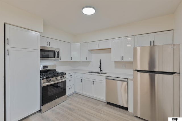 kitchen featuring a sink, appliances with stainless steel finishes, light countertops, and white cabinetry