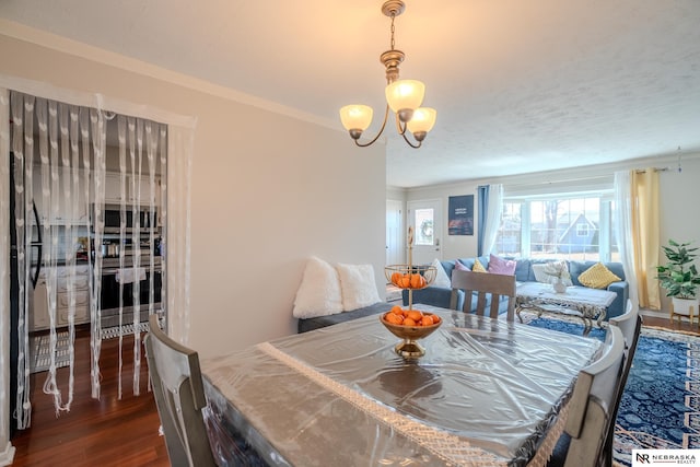 dining space featuring crown molding, a notable chandelier, and wood finished floors