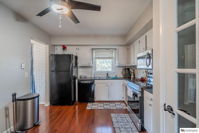 kitchen featuring dark countertops, tasteful backsplash, black appliances, white cabinetry, and a sink