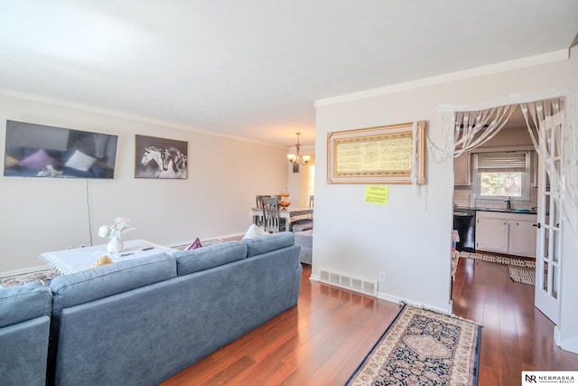 living area featuring visible vents, ornamental molding, dark wood-style floors, baseboards, and a chandelier