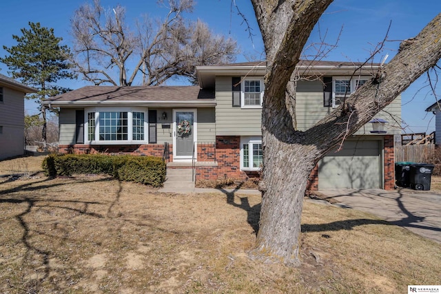 split level home with brick siding, an attached garage, driveway, and fence