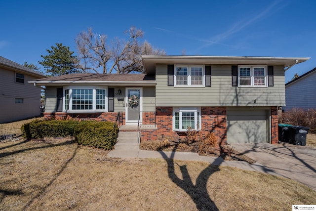 tri-level home featuring brick siding, an attached garage, and driveway