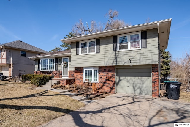 tri-level home featuring a garage, brick siding, and driveway