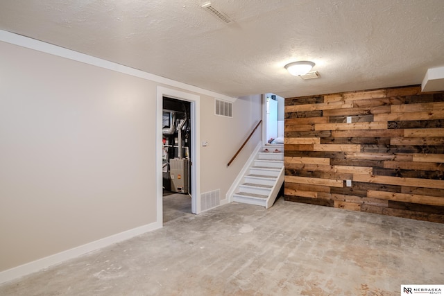 finished below grade area featuring visible vents, wooden walls, stairs, and a textured ceiling