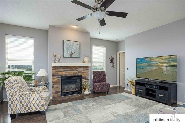 living area with baseboards, a ceiling fan, a glass covered fireplace, and wood finished floors