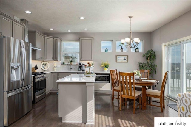 kitchen featuring an inviting chandelier, gray cabinets, light countertops, dark wood-type flooring, and stainless steel appliances