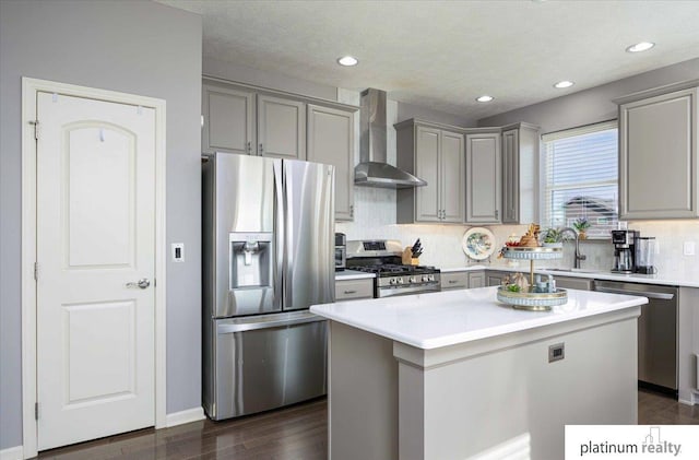 kitchen with stainless steel appliances, gray cabinetry, decorative backsplash, and wall chimney range hood