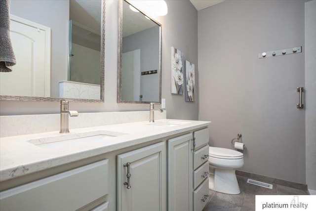bathroom with double vanity, visible vents, a sink, and toilet