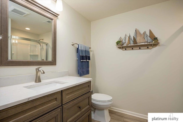 bathroom featuring a shower stall, vanity, visible vents, toilet, and wood finished floors