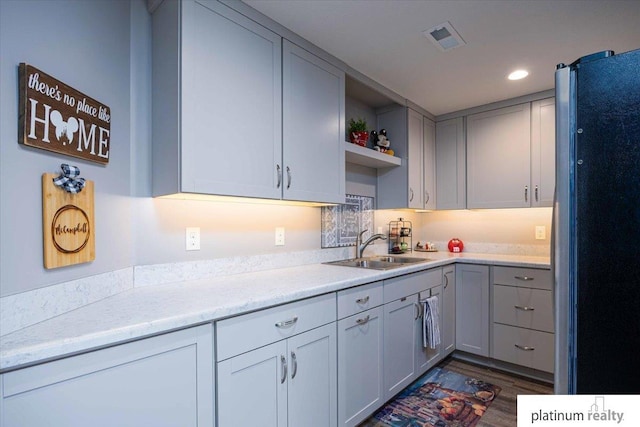 kitchen featuring visible vents, open shelves, a sink, light countertops, and freestanding refrigerator