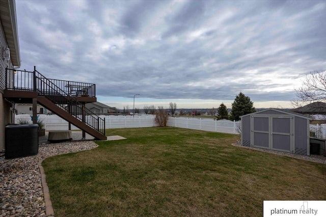 view of yard featuring a storage shed, a fenced backyard, an outdoor structure, and stairs