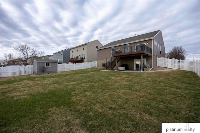 back of property with an outbuilding, a fenced backyard, a wooden deck, and stairway