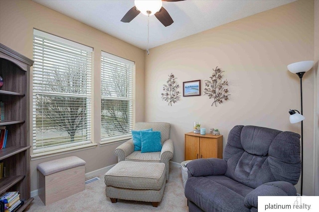 living area featuring ceiling fan, baseboards, and carpet