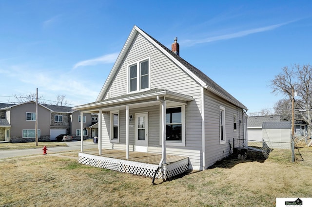 view of front of home with a porch, a chimney, a front lawn, and fence