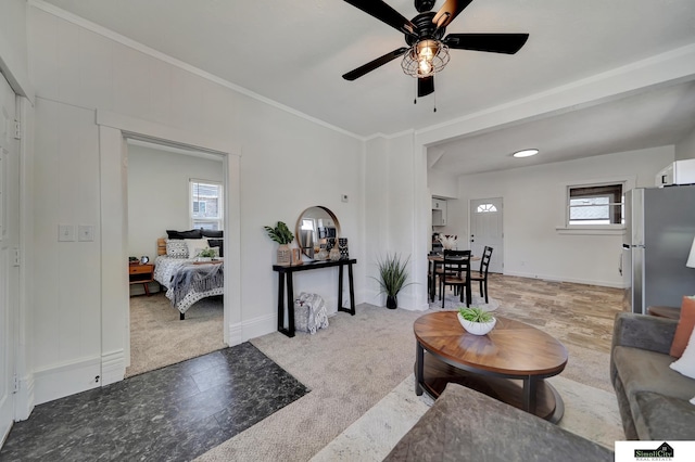 living area with light carpet, baseboards, a ceiling fan, and ornamental molding