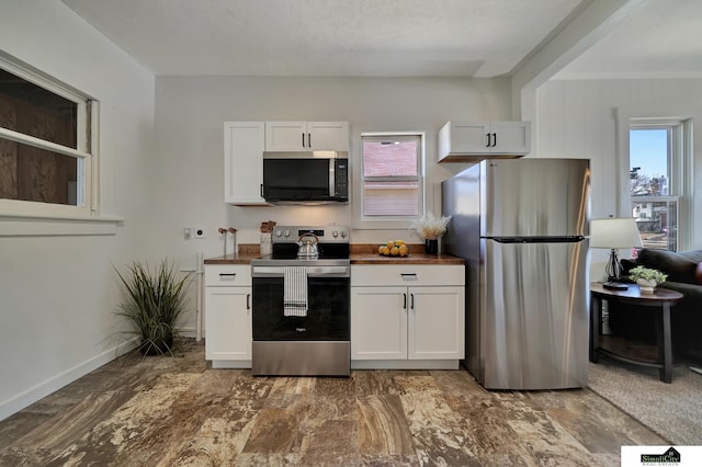 kitchen featuring visible vents, baseboards, appliances with stainless steel finishes, and white cabinetry