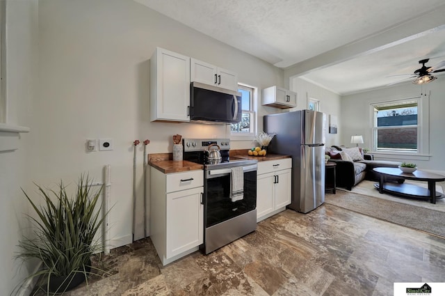 kitchen with a ceiling fan, white cabinets, appliances with stainless steel finishes, a textured ceiling, and open floor plan