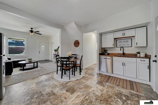 kitchen with butcher block countertops, a sink, stainless steel dishwasher, baseboards, and ceiling fan