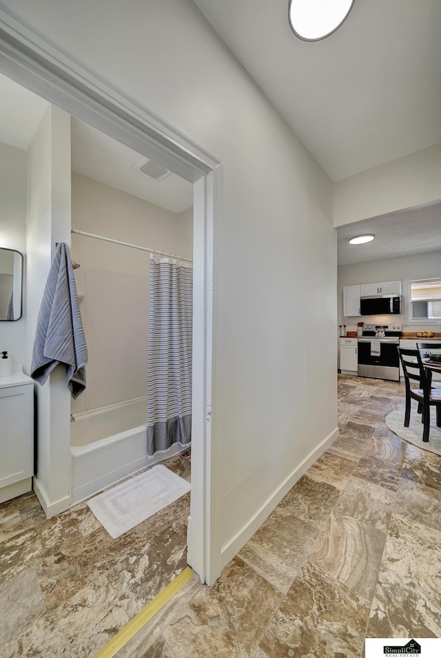 full bathroom featuring visible vents, baseboards, stone finish floor, and shower / bath combination with curtain