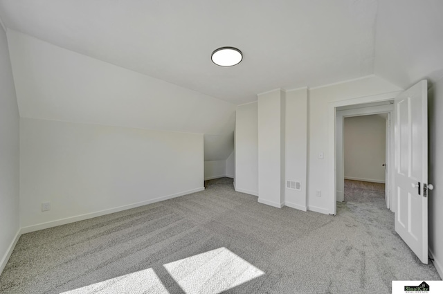 additional living space featuring vaulted ceiling, carpet flooring, baseboards, and visible vents