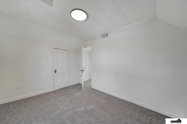 unfurnished room featuring visible vents, lofted ceiling, carpet, and baseboards