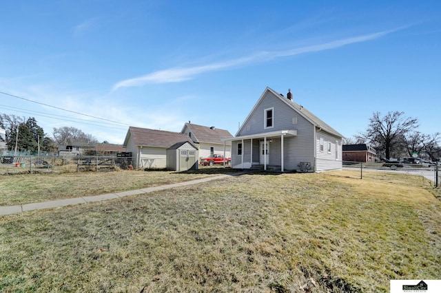 view of front of home featuring an outbuilding, a fenced backyard, a storage unit, and a front lawn