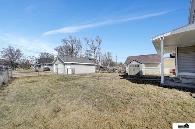 view of yard featuring an outdoor structure, a storage unit, fence, and a detached garage