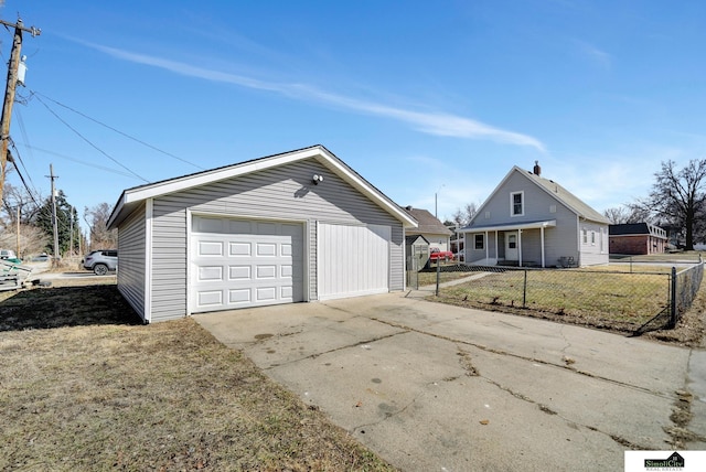 detached garage featuring concrete driveway and fence