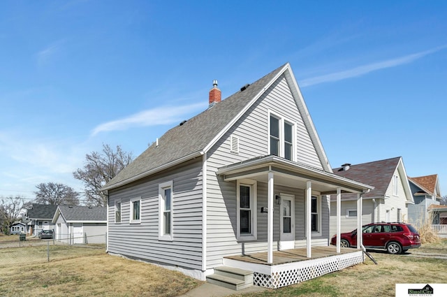 view of front of home featuring a chimney, a porch, a front lawn, and fence