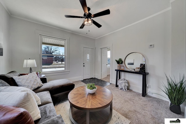 living room featuring light colored carpet, baseboards, a ceiling fan, and ornamental molding