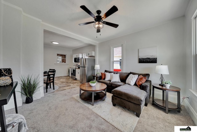 living area with baseboards, light colored carpet, and ceiling fan