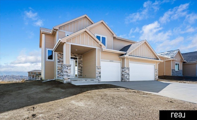 view of front of property with stone siding, board and batten siding, an attached garage, and driveway