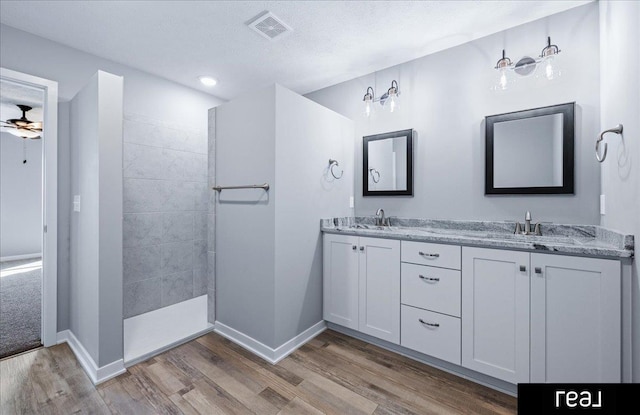 full bath with double vanity, wood finished floors, visible vents, and a sink