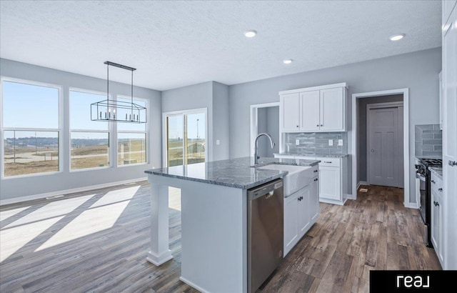 kitchen featuring a sink, gas range oven, decorative backsplash, light stone countertops, and dishwasher