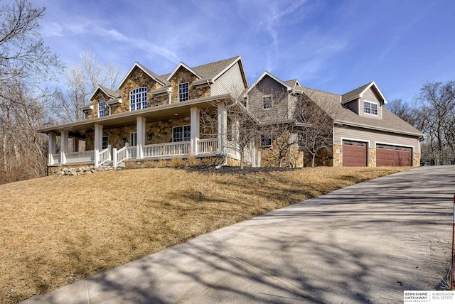 view of front of house with concrete driveway, covered porch, and stone siding