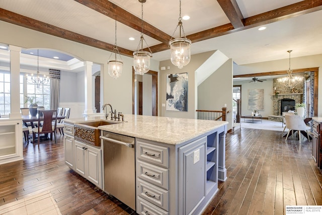 kitchen featuring open floor plan, dishwasher, decorative columns, dark wood-style flooring, and a sink