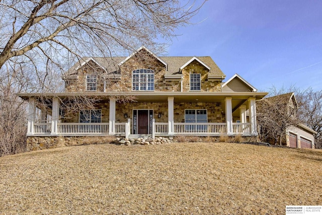 view of front of property featuring a porch, a garage, and stone siding