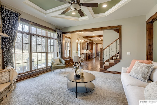 carpeted living room featuring a wealth of natural light, beamed ceiling, ceiling fan with notable chandelier, and coffered ceiling