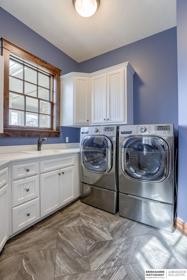 clothes washing area with cabinet space, washing machine and dryer, and a sink