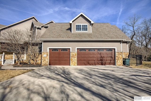 view of home's exterior featuring a garage, stone siding, roof with shingles, and driveway