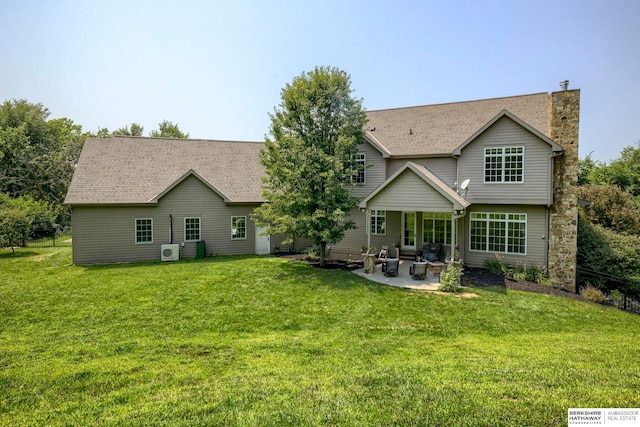 back of property featuring a patio, a lawn, a chimney, and a shingled roof